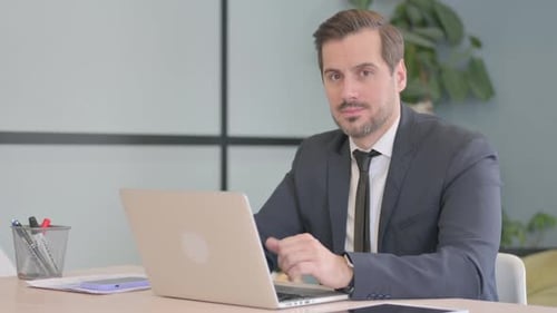 Businessman Working at Desk Gives Thumbs Up
