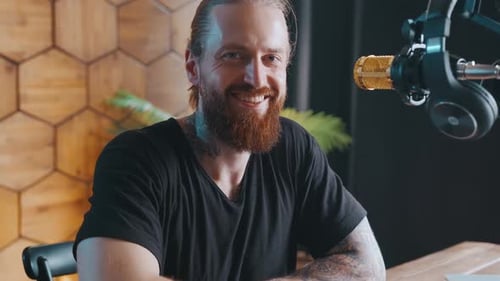 Stylish Man Smiling at Podcast Equipment At Home