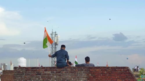 Young Adults Waving Indian Flags on Brick Building