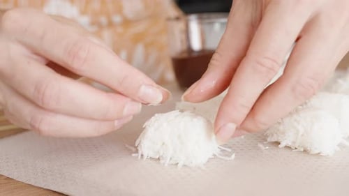 Die Frau macht Kokosnussbonbons aus geriebenem Kokosnussfleisch. Nahaufnahme
.