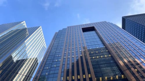 This 4K clip shows an office building with a blue sky and clouds passing by.
