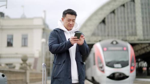 Man Using Smartphone at Modern Train Station