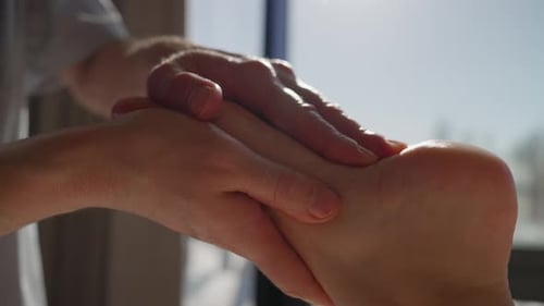 Closeup Relaxing Foot Massage with Gentle Therapeutic Hand Movements in Natural Daylight Near Large