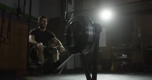 Extreme Atheltics - Male rowing on machine in gym athlete