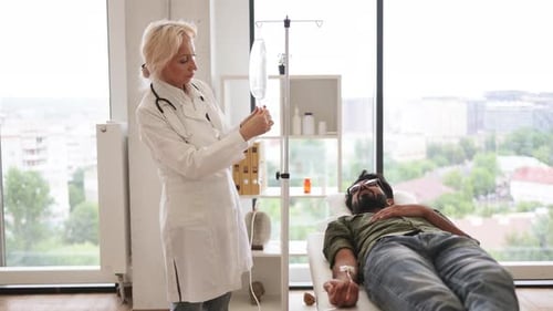 Elderly Woman in Lab Coat Testing Dropper with Solution for Chemotherapy