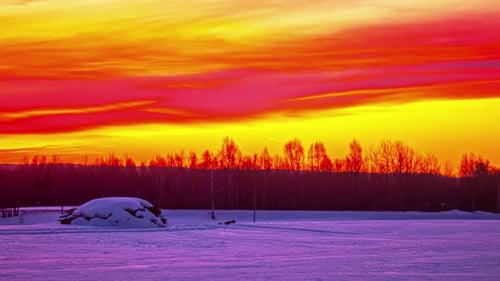 Time-lapse of moving red yellow colorful clouds in sky at sunrise in snowy countryside landscape