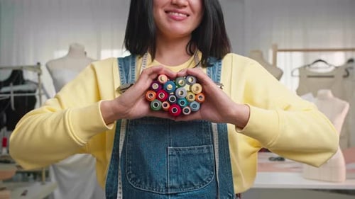 Creative Woman Holding Colorful Thread Spools in Studio