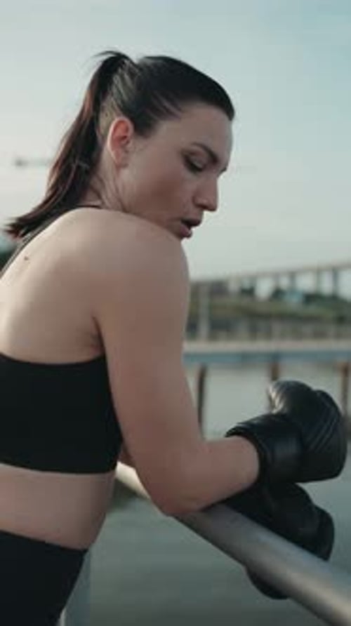 Strong Woman Boxer Resting on Bridge with Boxing Gloves