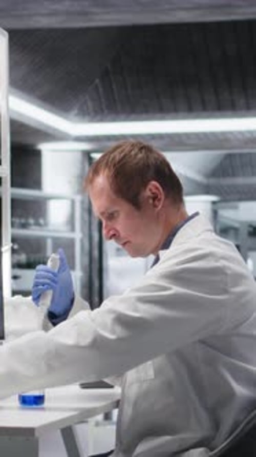 Man in Lab Coat Working with Pipette
