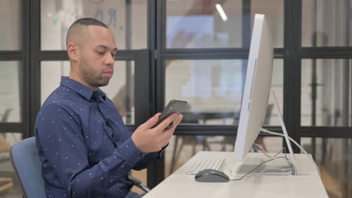 Young Adult Using Mobile Phone at Desk