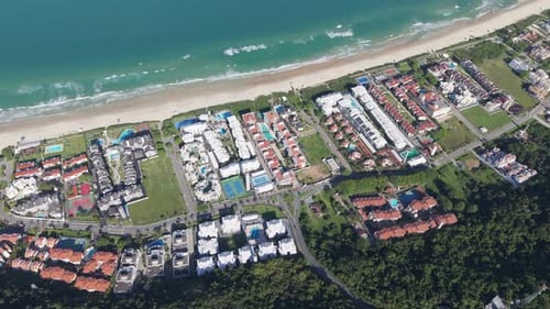 Vertically tilted down aerial view of seaside neighborhood with populated houses alongside a sandy P