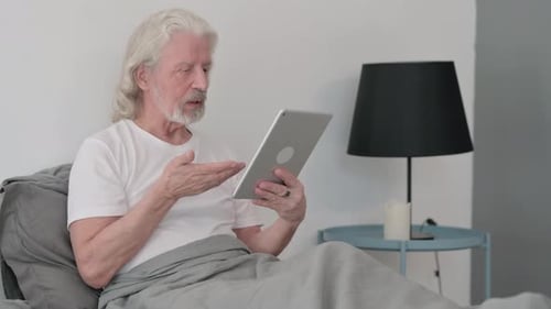 Senior Man Video Chatting in Bed on Tablet