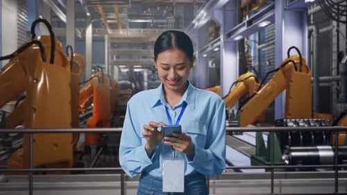 Woman Monitors Robotic Arms in Futuristic Factory