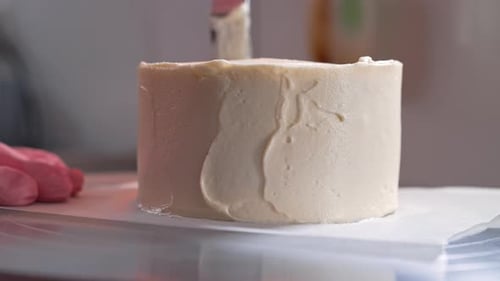 Cake Covered in White Frosting Being Smoothed