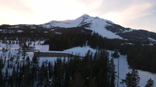 A drone shot of snowy Big Sky, Montana in winter, showcasing the ski resort and majestic mountain te