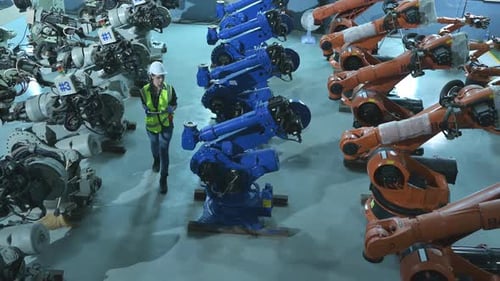 A female engineer installs a program on a robotics arm in a robot warehouse.