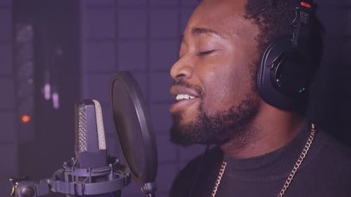 African American Man with Professional Headphones is Singing New Romantic Pop Song in Record Studio