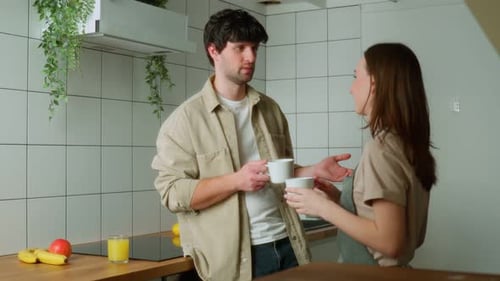 Young Couple Talking and Drinking Coffee in Kitchen