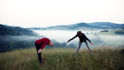 Active Senior Couple Stretching on a Mountain Meadow