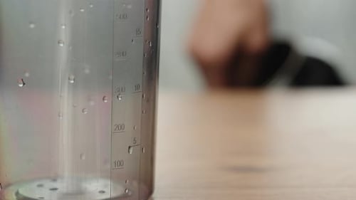 I pour protein powder for a sports cocktail into a whipping glass. close-up