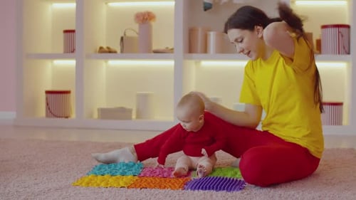 Mother Helping Baby Walk on Textured Mat at Home