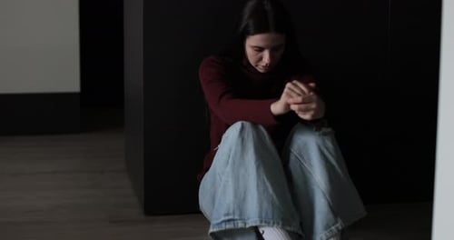Sad Woman Sitting in the Dark Leaning Against the Wall in Home Domestic Violence Family Problems