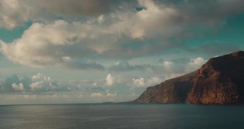 Ocean and Blue Sunny Sky with Fluffy White Clouds Near Los Gigantes Cliffs in Tenerife at Sundown