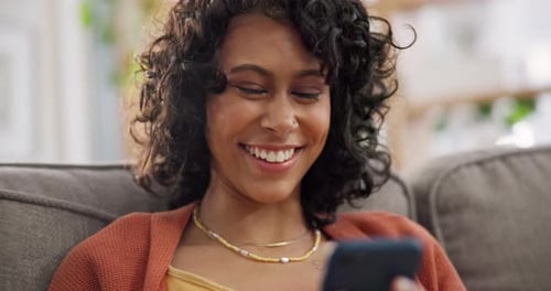 Woman Using Smartphone Smiling on Couch Indoors