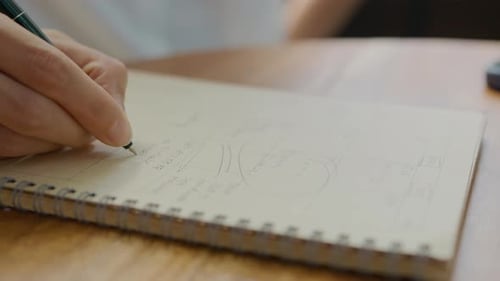 Manos escribiendo notas comerciales en cuaderno