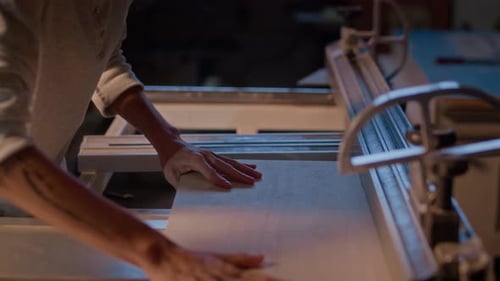 Hands cutting wood on machine in workshop