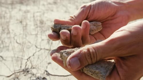Hands Crumbling Dry Earth in Arid Landscape
