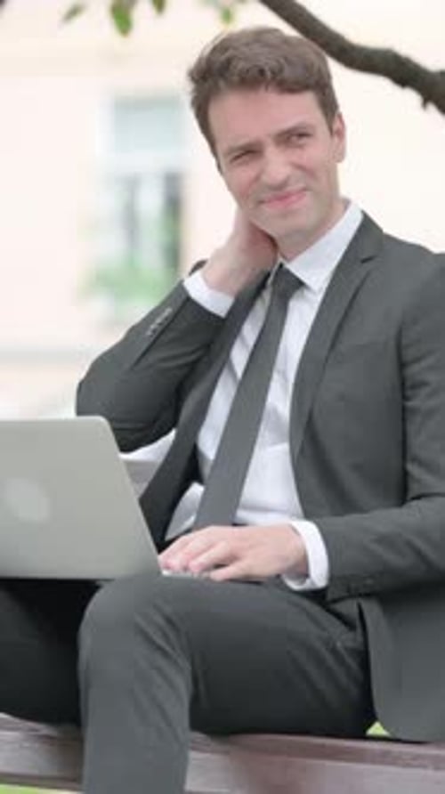 Man in Suit Sitting on Bench with Neck Pain