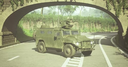 Military Vehicle Navigating a Winding Road Beneath a Verdant Archway