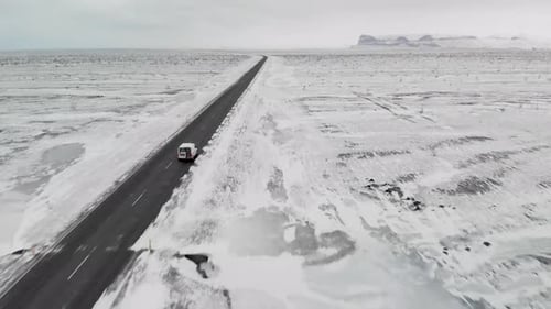 Aerial shooths of a van on Iceland road. Is winter and snow is all over the road.