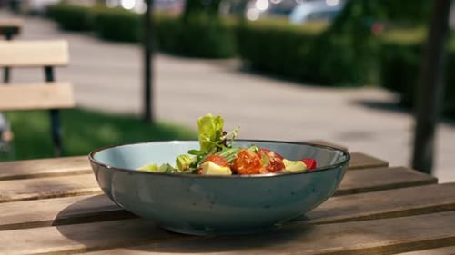 in a Restaurant on the Street on Plank Table a Blue Vertical Video Plate with a Warm Salad with