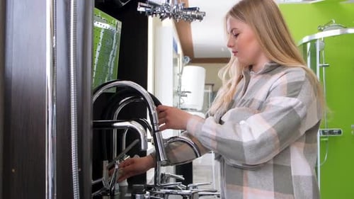 A Woman Examines the Assortment in a Plumbing Store Buying Sanitary Ware in a Hardware Supermarket