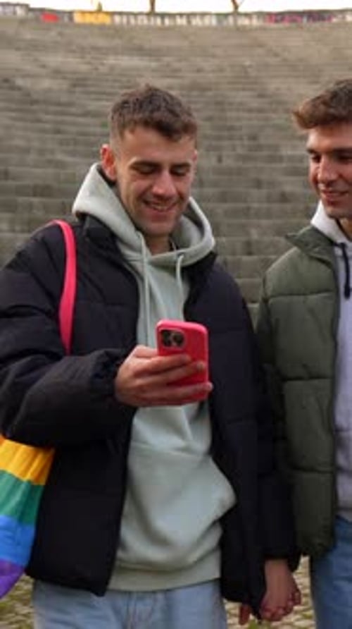 Gay couple holding hands and browsing smartphone
