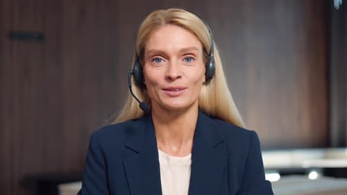 Female Operator of Call Center in Headset Sitting at Workplace and Talking