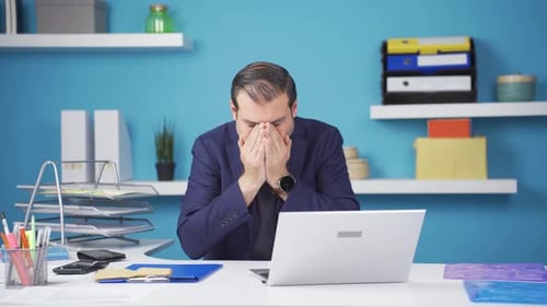 Stressed Man at Desk with Laptop in Office