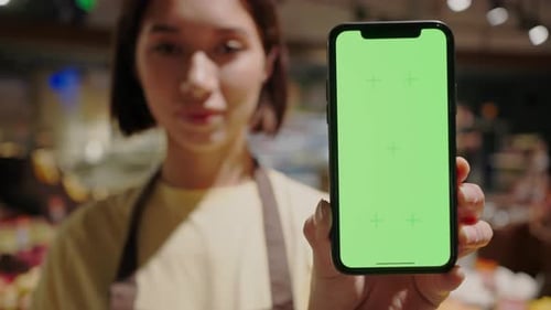 Woman Holds Mobile Phone with Green Background for Insertion