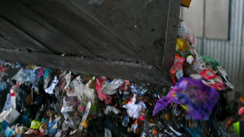An excavator unloading waste into a large heap of garbage at waste sorting plant. Slow motion