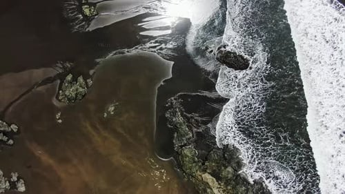 Aerial Drone Flying Above Gorgeous Black Sand Beach With White Water Waves Crashing Onto Shore.