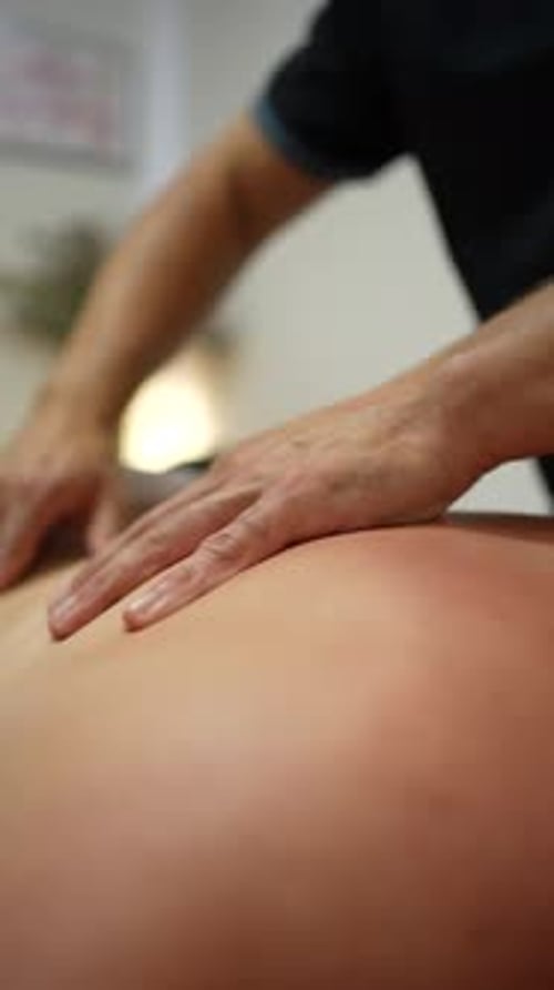 Physiotherapeut massiert den Rücken des Klienten mit seinen Händen physiotherapeutisch