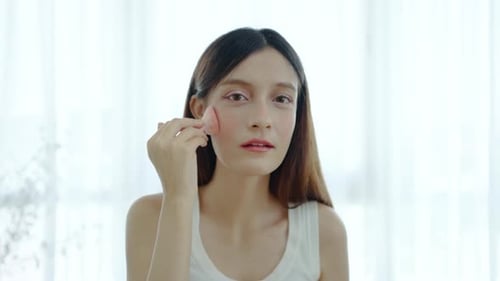 Woman Applies Makeup in Bright Room