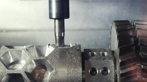 Metallspäne fliegen beim Bohren eines Metallteils durch die Fräsmaschine