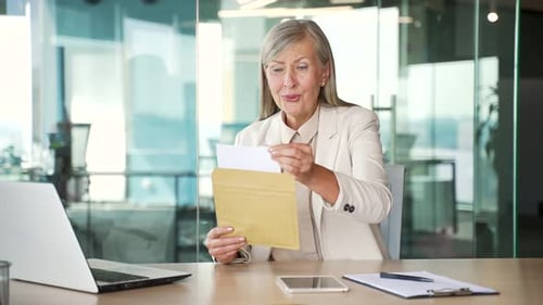 Excited Woman Reads Letter at Office Desk