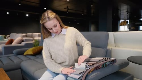 Woman Selecting Fabric on Sofa in Furniture Store