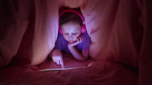 Girl Using Tablet Under Blanket at Night