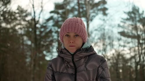 Portrait of a young woman in warm clothes in a winter forest.
