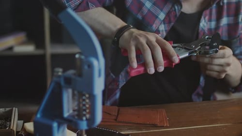 Artisan en cuir faisant des trous dans la sangle